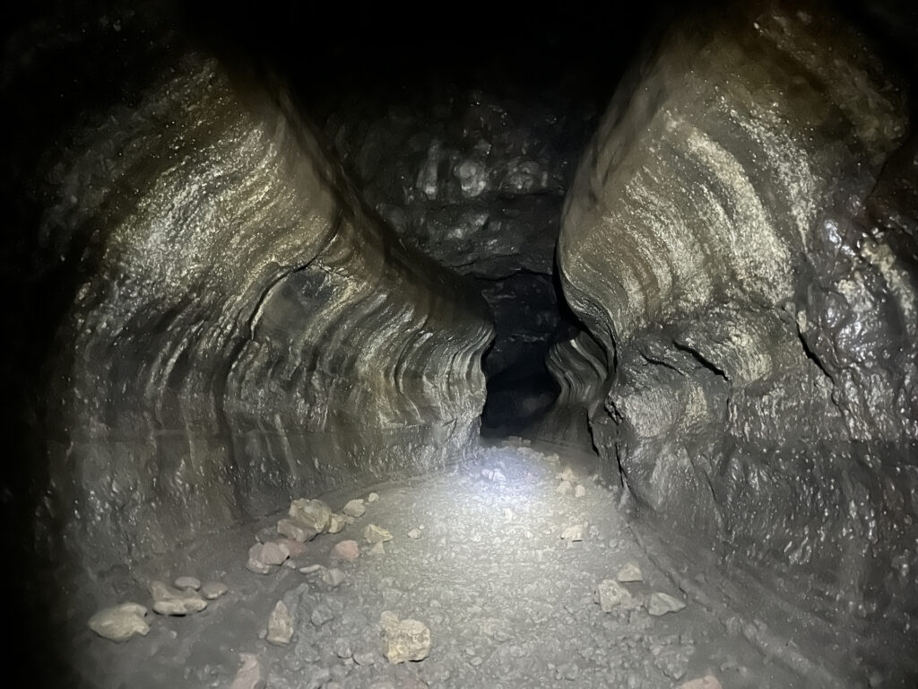 Looking up Ape Cave - a winding lava tube with rounded walls. A bit of rock rubble is scattered on the flat cave floor.