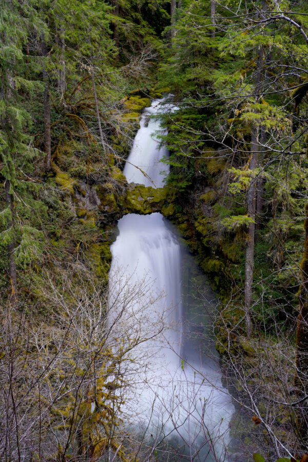 Curly Creek Falls drops in two steps with a stone arch across the face of the waterfall in the center.