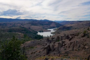 A group of hoodoos stand above the Metolius River in Central Oregon within a rolling desert landscape.