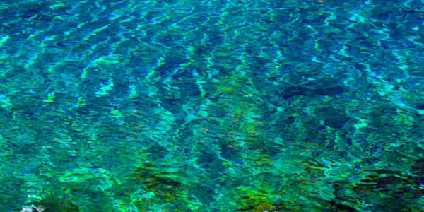 The pure waters of Tamolitch Blue Pool ripple in bright shades of blue, turquoise, and green.