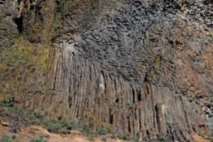 Layers of chunky basalt flows rest above stripes of columnar basalt in this detail of a cliff along the Crooked River.