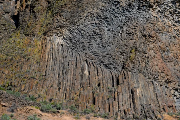 Layers of chunky basalt flows rest above stripes of columnar basalt in this detail of a cliff along the Crooked River.