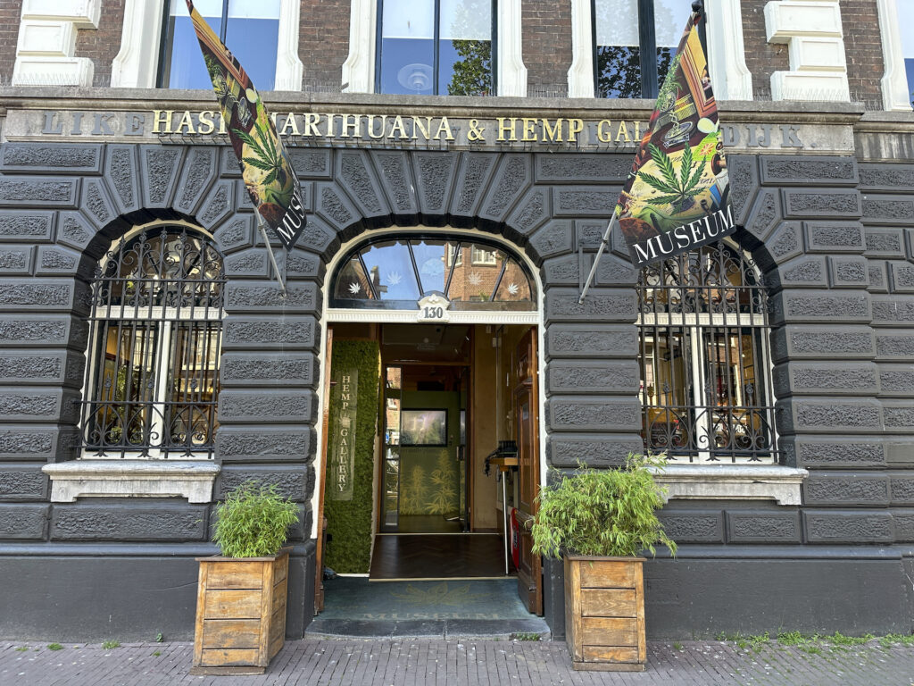 The front entrance of "Hash Marihuana & Hemp Gallery" in Amsterdam, with flags flying on either side of the door.