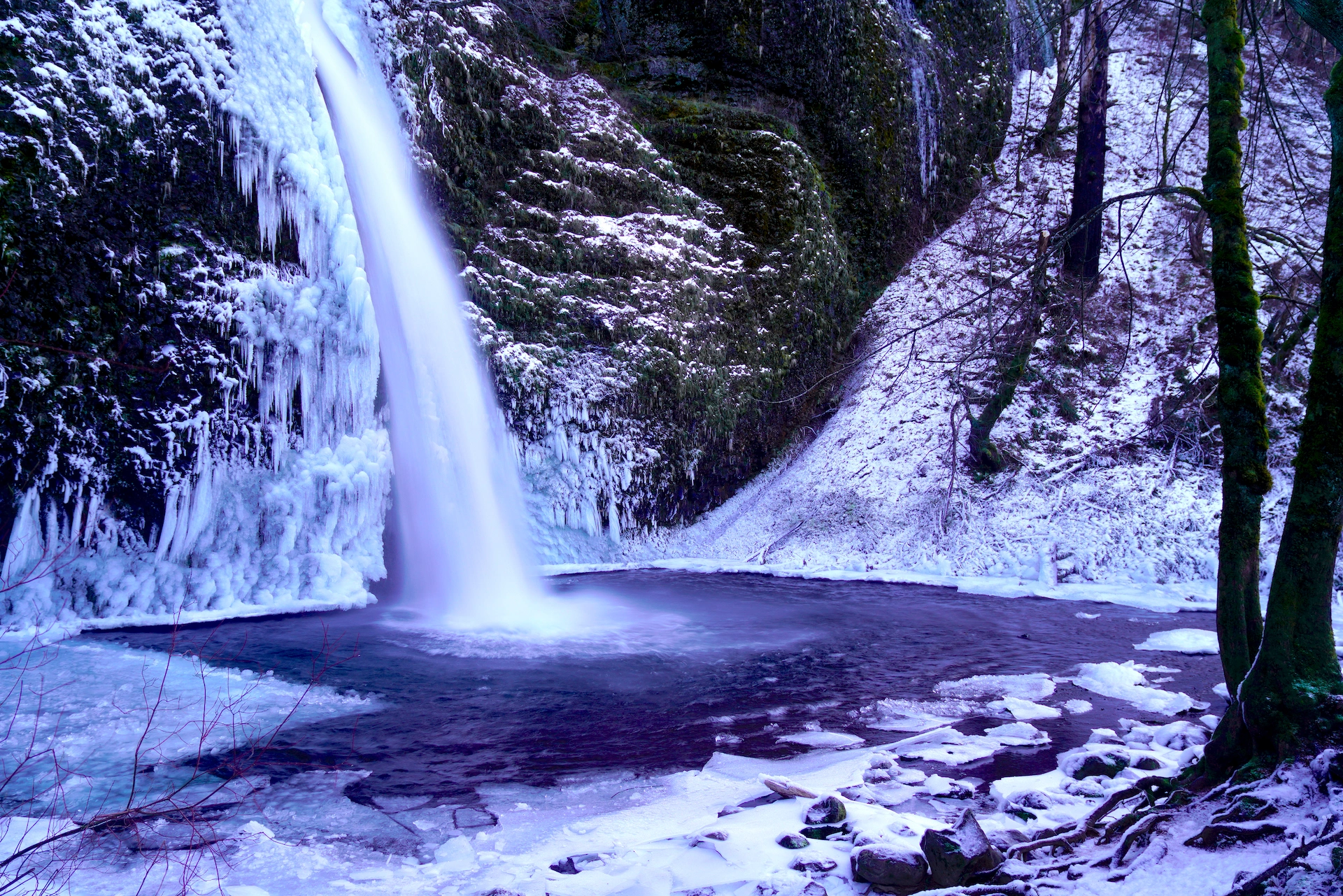 Horsetail Falls slides steeply down a frozen cliff into an icy pool in this winter waterfall scene.