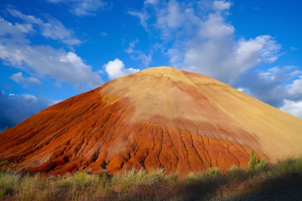 Red Hill is pictured beneath a blue sky dotted with expanding clouds.