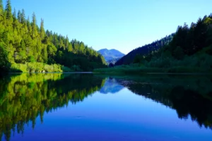 Dillon Mountain and forested slopes are reflected in the calm water of the Klamath River in Northern California.