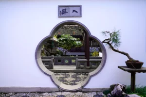 A stylized round and lobed portal in a white wall looks into Lan Su Chinese Garden in Portland, Oregon.