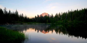 The top of Oregon's Mt Hood is bathed in pink sunset light, with it's reflection showing on Mirror Lake.