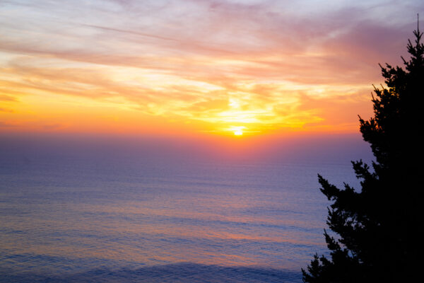 Colorful clouds swirl as the sun sets into the Pacific Ocean on the Oregon Coast.