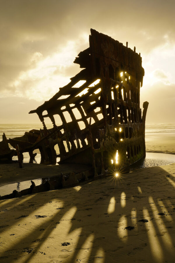 The silhouette of Peter Iredale shipweck during a golden sunset.