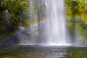 A rainbow stretches across base of misty Puff Falls in Washington's Gifford Pinchot National Forest.