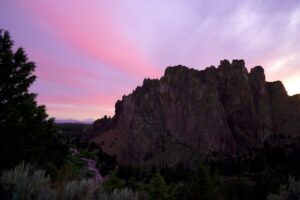 The colors of a pink and purple sunset are reflected in the Crooked River at Smith Rock State Park.