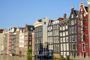 A view looking down a canal in Amsterdam at row of canal houses, most about five stories tall.