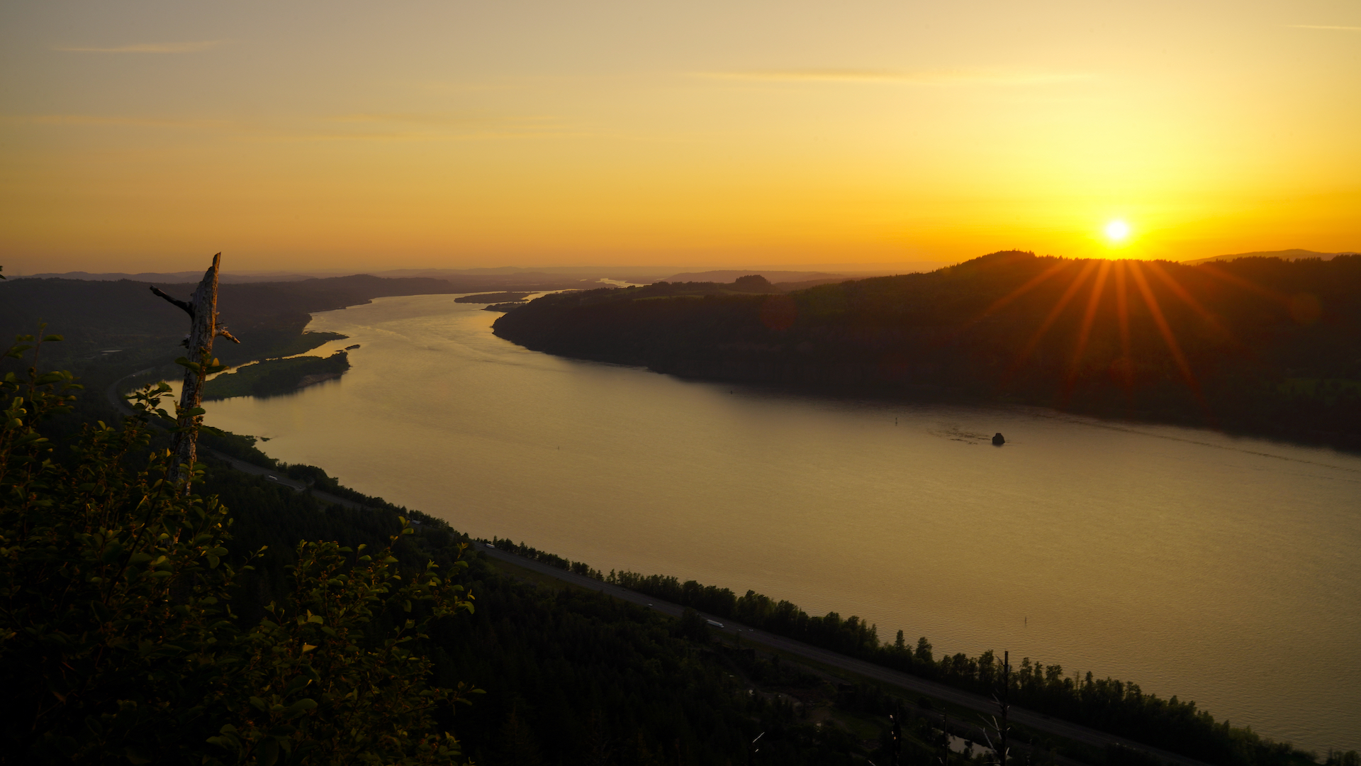 The sun sets behind hills along the mighty Columbia River as viewed from the Angel's Rest Trail in Oregon.