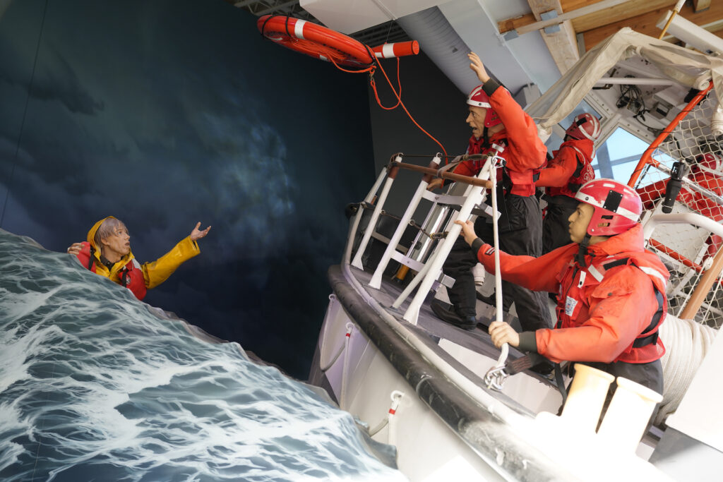 A full-scale model of a US Coast Guard rescue team in action is featured at Columbia River Maritime Museum. In the scene rescuers are throwing a life preserver to a person who's stranded in a raging sea.