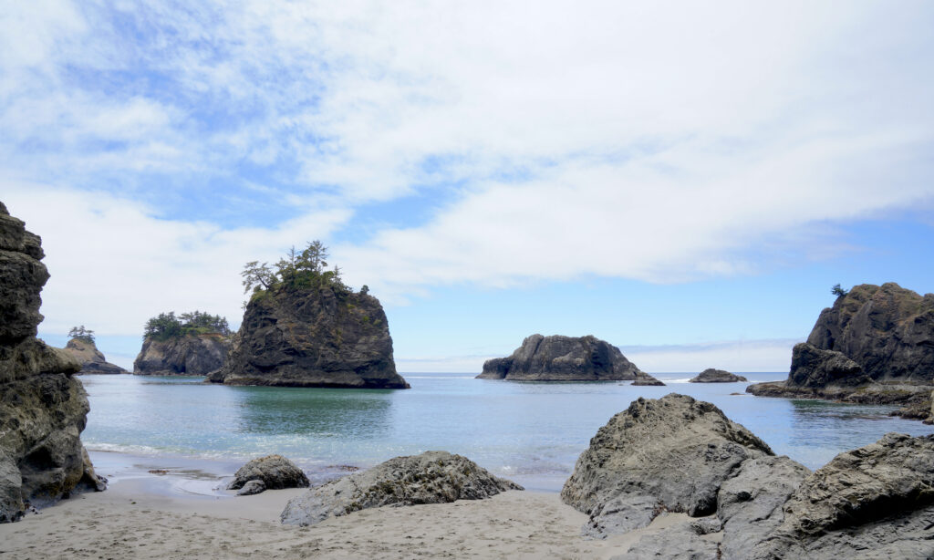 Large monolith rise from the calm ocean at Secret Beach on the Oregon Coast.