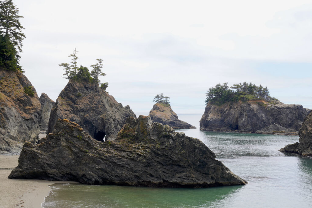 Conifers top the offshore rocks at placid Secret Beach on the Oregon Coast.