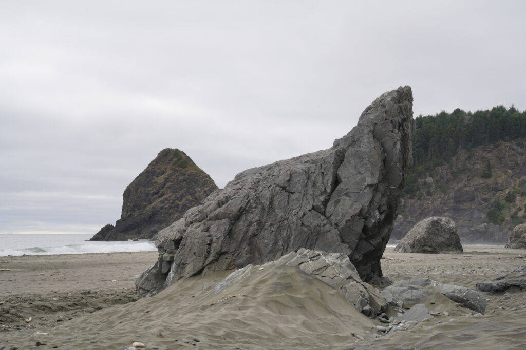 A large, pointy rock stick up out of the sand at Whaleshead Beach.