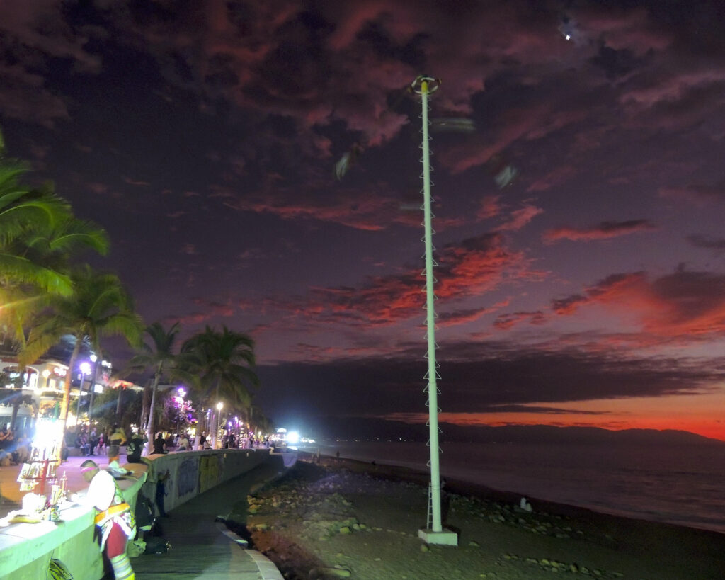 Four Skydancers spiral down through the air during a red sunset along the Malecon in Puerto Vallarta, Mexico.