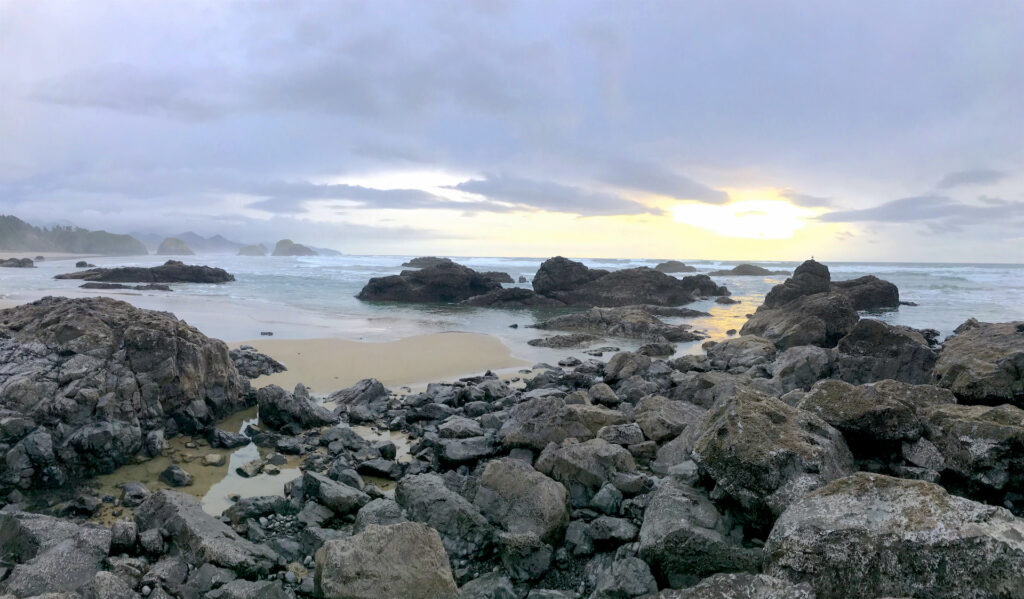 A yellow glow brightens a small patch of clouds in an otherwise cold winter sunset at Crescent Beach in Ecola State Park, Oregon.