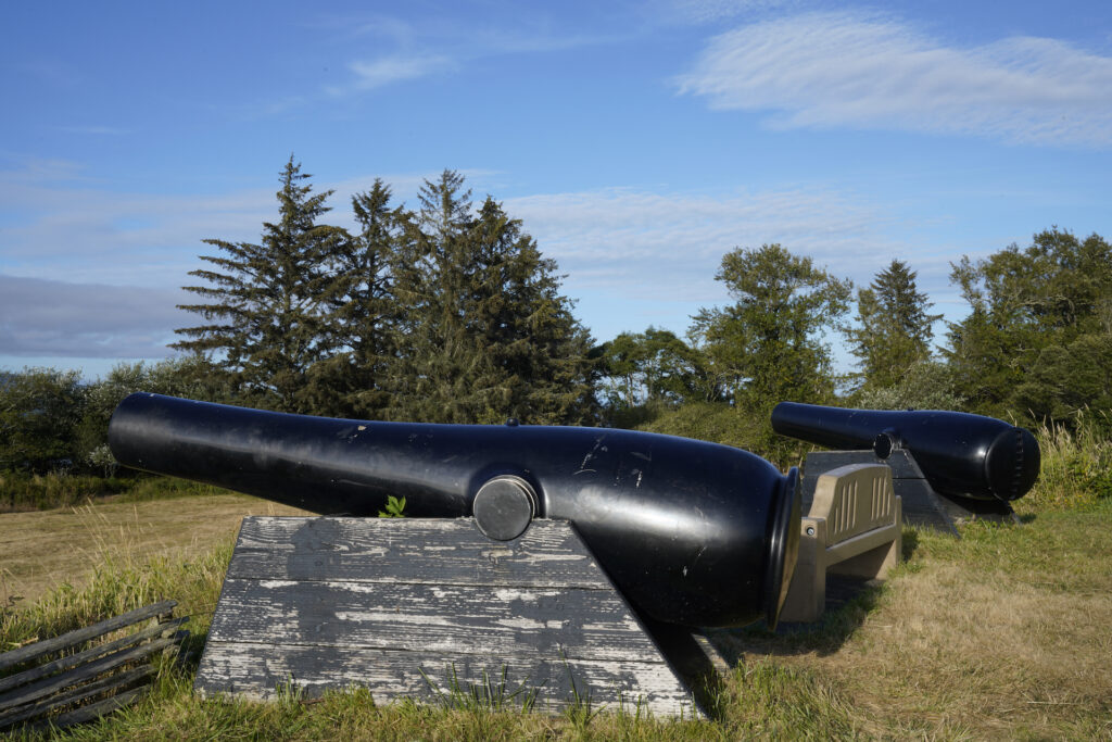 A pair of black cannons are mounted on a defensive battery at Fort Stevens State Park near Astoria, Oregon.