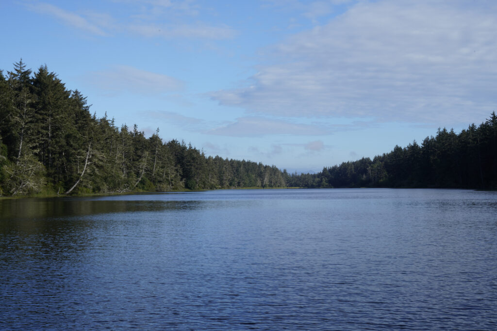 Coffenbury Lake reflects the blue sky above it in Fort Stevens State Park near Astoria, Oregon.