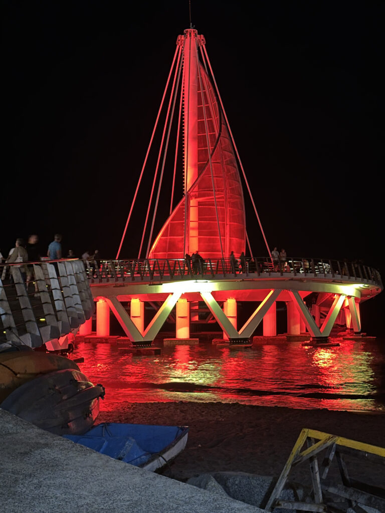 The spiral shape of Muelle de Playa los Muertos is lit up in red at night in Puerto Vallarta.