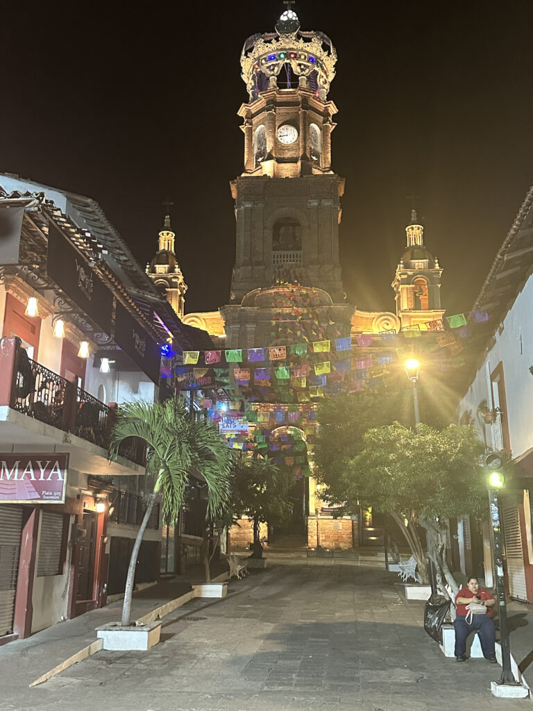 The crowned top of Parroquia de Nuestra Senora de Guadalupe rises above old town Puerto Vallarta at night.