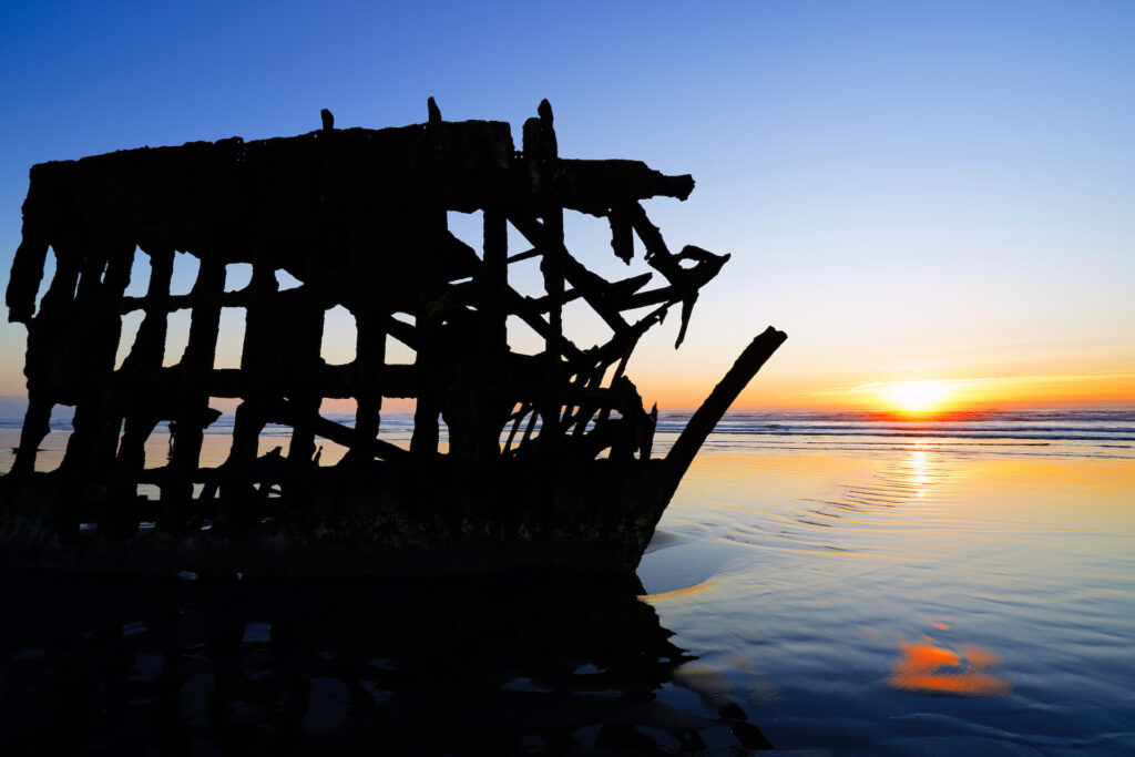 The sun sets behind the wreck of Peter Iredale at Fort Stevens State Park, Oregon.