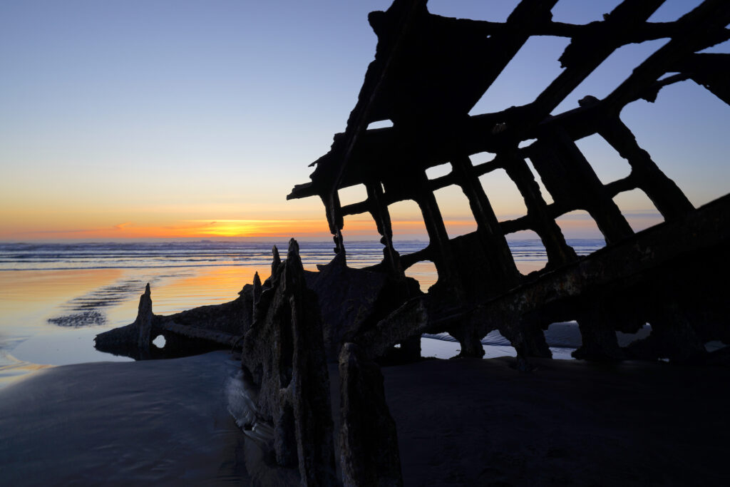 The sun sets behind the wreck of Peter Iredale at Fort Stevens State Park, Oregon.