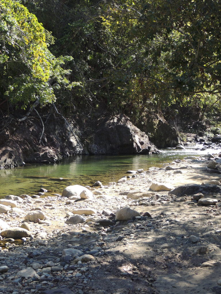 A rocky beach rests next to a turquoise pool on Rio Cuale east of Puerto Vallarta.