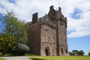 A side view of the front of red-toned Brodick Castle on Isle of Arran, Scotland on a pleasant day.