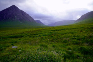 Looking down the upper part of emerald green Glen Coe with a tall peak named Buachaille Etive Mor on the left.