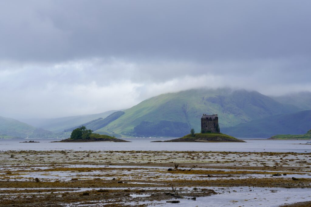 A pair of small grassy islands rise out of Loch Linnhe in Scotland, with Castle Stalker on the left island.