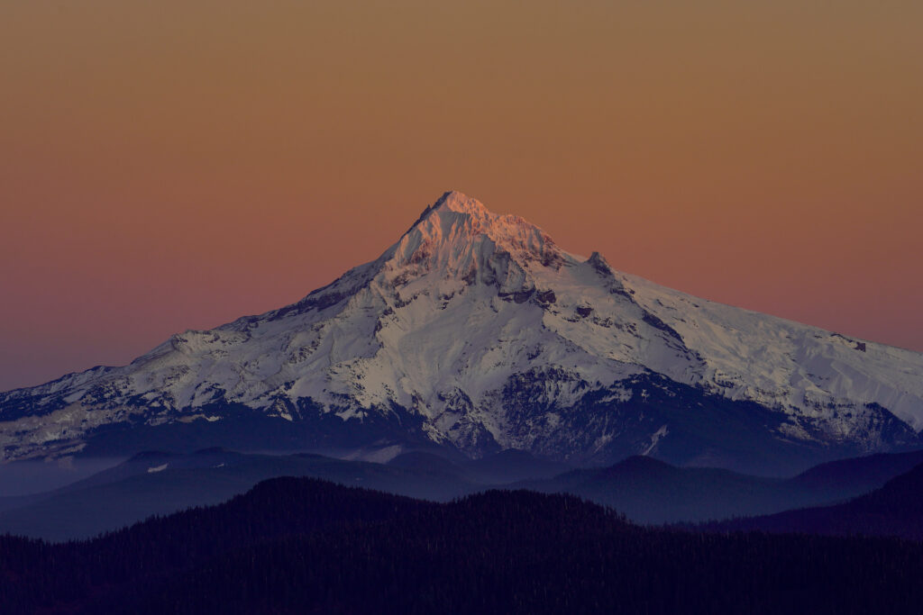 The last ray of pink sunset light touches the top of Mt Hood, Oregon.