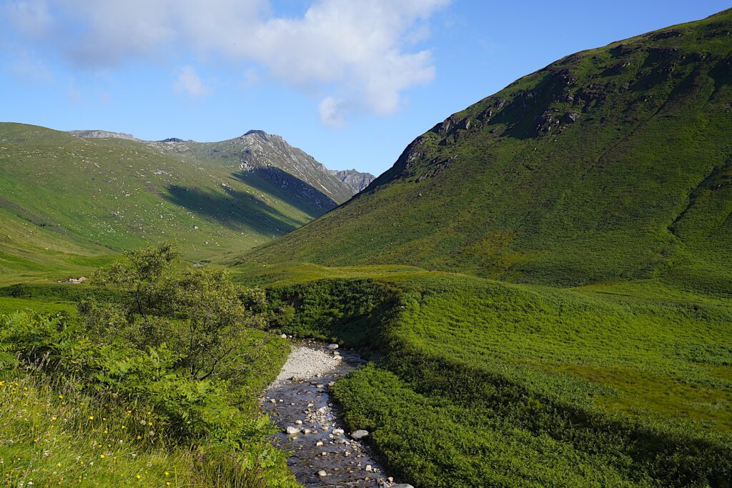 Glen Rosa on Scotland's Isle of Arran is carpeted in green with a small river flowing through it.