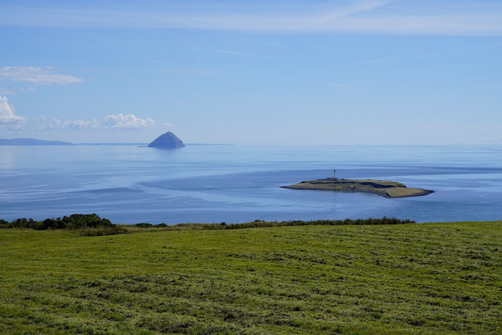 Plodda Island and Lighthouse rises from glassy seas in Scotland.