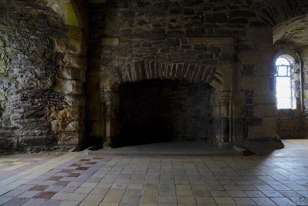 A large stone fireplace fills the wall in a chamber in medieval Duone Castle in Scotland.