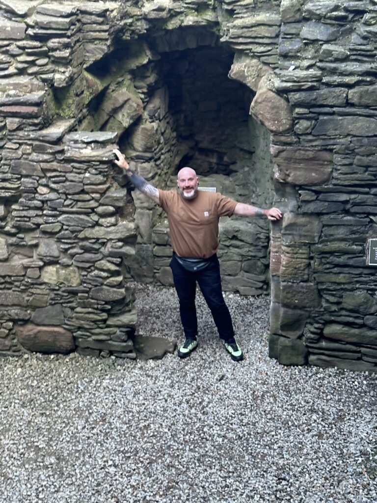 A man stands in a doorway in a stone castle ruin in Scotland.