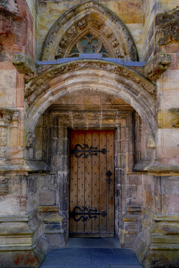 The door into historic Rosslyn Chapel in Scotland is surrounded by rich stonework.