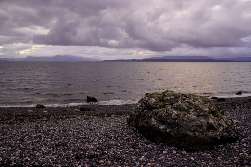 Sunset storm clouds over the pebble beach below Ganavan Maze near Oban, Scotland.