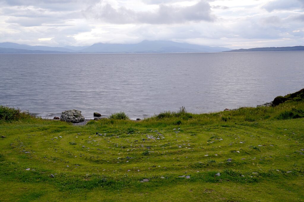 A spiral pattern made of pebbles on the ground is slowly being erased by grass and moss near Oban, Scotland.