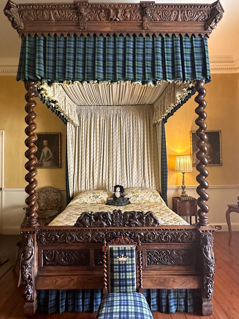 An ornately carved wooden four-post canopy bed in Scotland's Inveraray Castle.