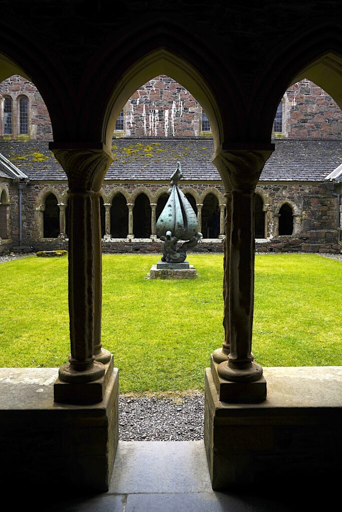 Looking through arches into the grassy cloister courtyard in Scotland's historic Iona Abbey.