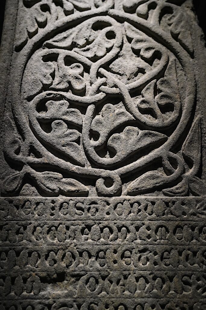 A carved stone grave marker at Iona Abbey in Scotland shows a geometric pattern of interwoven vines.