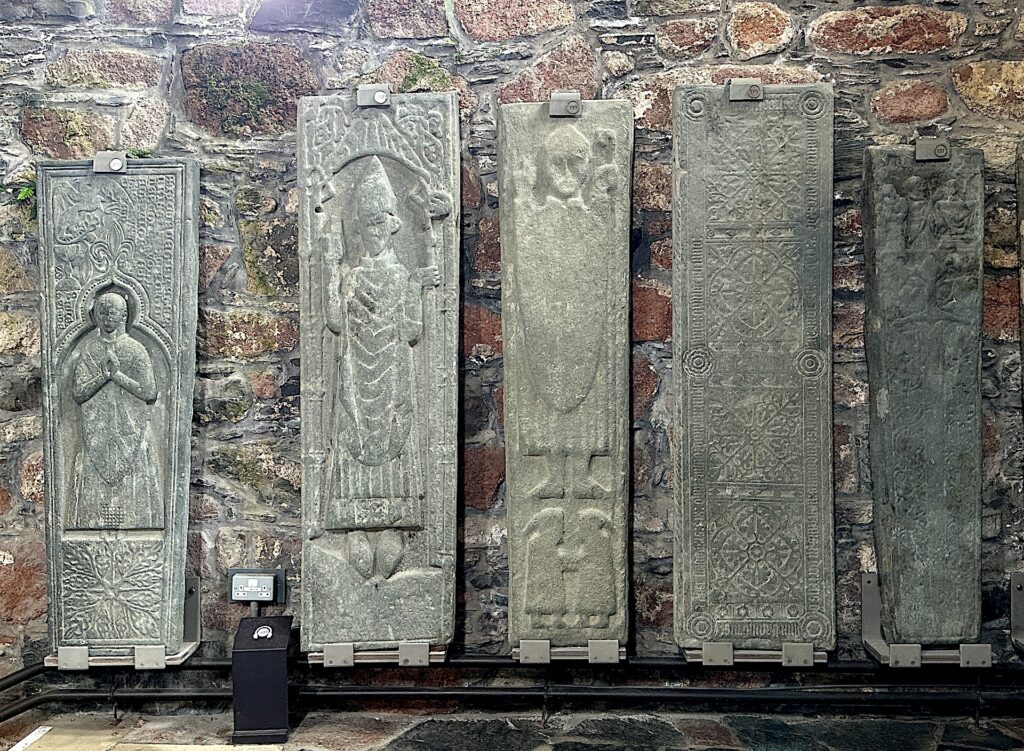 A row of five elaborately carved stone grave markers from the Viking era are displayed in Iona Abbey, Scotland.