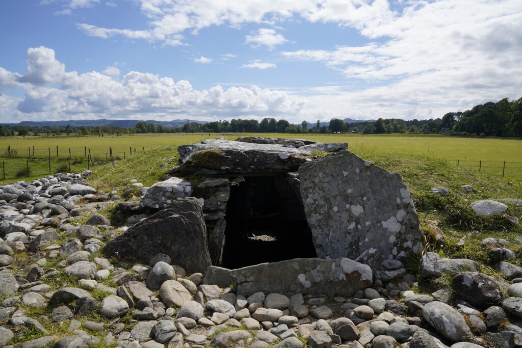 A dark opening in the rock slabs leads into Nether Largie South Cairn in Kilmartin Glen, Scotland.