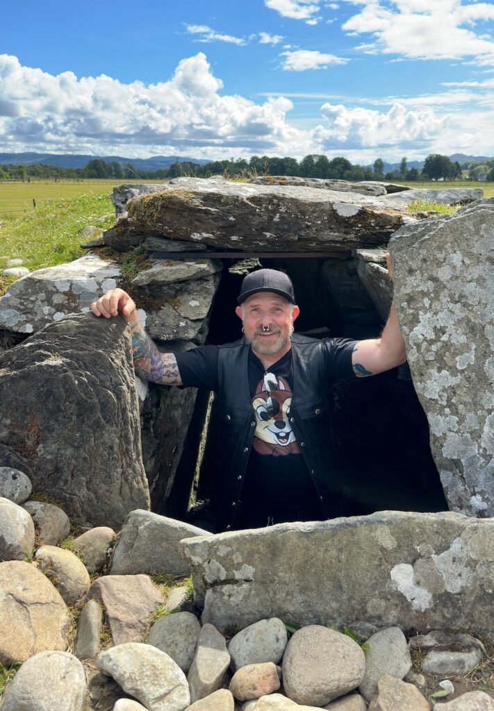 A man stands in the entrance to a stone cairn in Kilmartin Glen, Scotland.