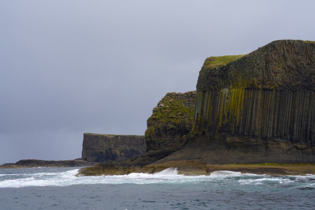 Dramatic columnar basalt cliffs drop into the Atlantic on the west coast of the Isle of Staffa in Scotland.