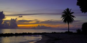Horizontal bands of clouds create a striped sunset as seen from Fare on Huahine, French Polynesia.